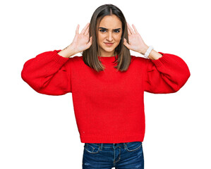 Beautiful brunette woman wearing casual winter sweater trying to hear both hands on ear gesture, curious for gossip. hearing problem, deaf