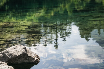 Reflection in the mountain lake of coniferous forest and mountain landscape, clear mountain lake as a mirror