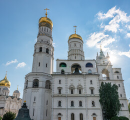 Ivan the Great Bell Tower, with Assumption Belfry on the right in Moscow Kremlin. Blue sky background with sunbeams