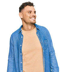 Young hispanic man wearing casual clothes looking away to side with smile on face, natural expression. laughing confident.