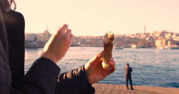Woman eating simit, turkish bagel with istanbul city view, close-up shot
