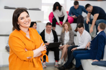 Obraz premium a brunette woman in an orange blouse with men and women in the office.