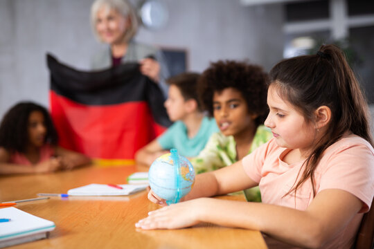 Portrait of a ten-year-old schoolgirl studying Germany history in lesson and looking for her on the globe