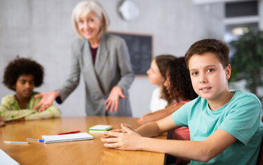 Fototapeta premium While working in classroom, teacher explains to children new information on subject