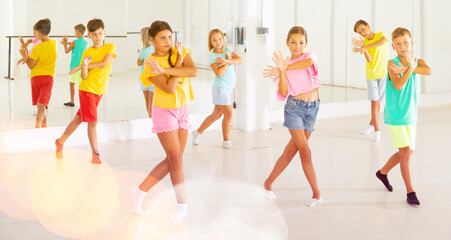 Fototapeta premium Group of kids training modern dance moves together in studio.