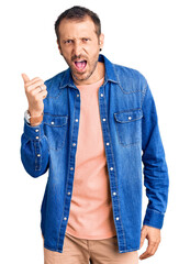 Young handsome man wearing casual clothes angry and mad raising fist frustrated and furious while shouting with anger. rage and aggressive concept.