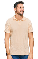 Fototapeta premium Young hispanic man wearing casual clothes looking away to side with smile on face, natural expression. laughing confident.
