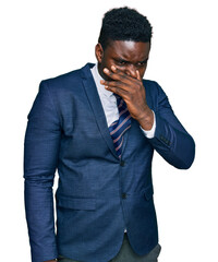 Handsome business black man wearing business suit and tie smelling something stinky and disgusting,...