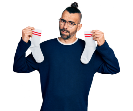 Hispanic man with ponytail holding socks in shock face, looking skeptical and sarcastic, surprised with open mouth