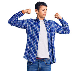 Young african amercian man wearing casual clothes showing arms muscles smiling proud. fitness concept.