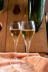 Glasses of sparkling white wine champagne or cava with bubbles and classic wooden champagne pupitre rack with empty bottles on background