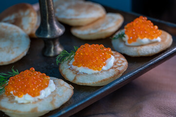 Tasty appetizer for dinner, small pancakes bliny with red fish caviar and sour cream