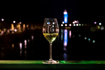 Tasting of french sparkling white wine with bubbles champagne outdoor at night with view on Marne river and lights of Epernay city in winter