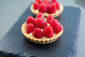 Artisanal baked small tart with cream and fresh ripe red raspberry