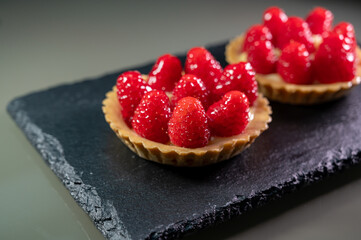 Artisanal baked small tart with cream and fresh ripe red raspberry