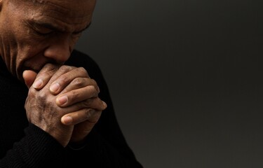 praying to god with hands together Caribbean man praying with black background stock photos stock photo