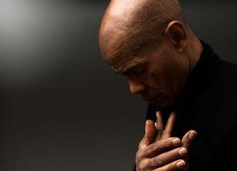 praying to god with hands together Caribbean man praying with black background stock photos stock photo