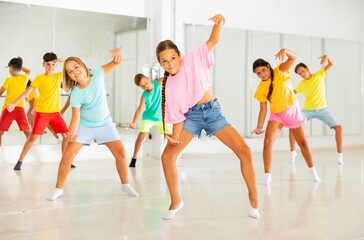 Fototapeta premium Smiling girls and boys doing dance workout during group class in fitness center
