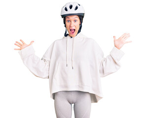 Beautiful brunette young woman wearing bike helmet and sporty clothes celebrating crazy and amazed for success with arms raised and open eyes screaming excited. winner concept