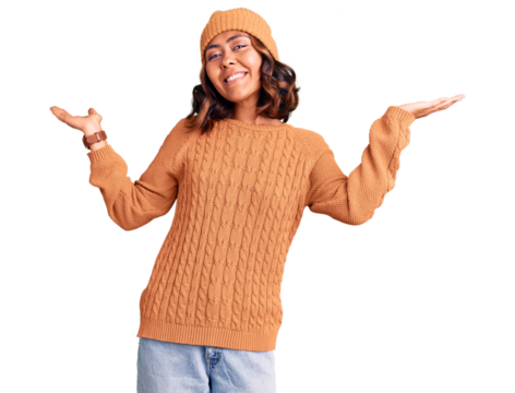 Young beautiful mixed race woman wearing wool sweater and winter hat clueless and confused expression with arms and hands raised. doubt concept.
