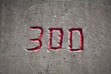 the number 300 in red on a concrete wall