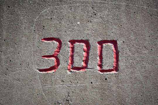 the number 300 in red on a concrete wall