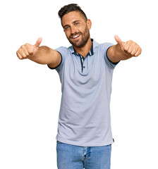 Handsome man with beard wearing casual clothes approving doing positive gesture with hand, thumbs up smiling and happy for success. winner gesture.