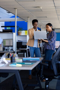 Diverse business people using laptop and discussing work at office