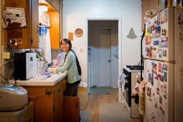 Obraz premium Young asian girl washing dishes after dinner