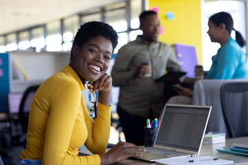 Portrait of african american businesswoman using laptop and smiling at office