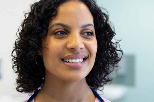 Happy biracial female doctor with stethoscope smiling in hospital
