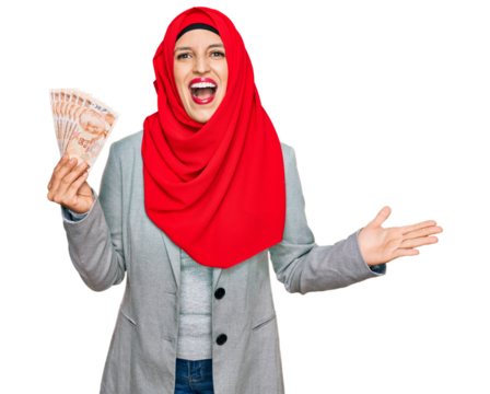 Beautiful hispanic woman wearing islamic hijab holding turkish lira banknotes celebrating victory with happy smile and winner expression with raised hands - Powered by Adobe