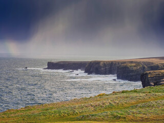 Beautiful scenery of Kilkee cliffs in county Clare, Ireland. Stunning Irish nature landscape. Day time, dramatic sky with clouds. Popular tourist and travel area with amazing view. Nature scene.