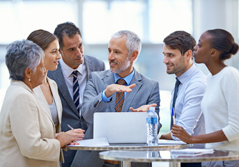 Projecting future growth. Shot of a mature businessman explaining a concept to his colleagues in a...