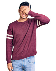 Hispanic handsome young man wearing casual clothes smiling and laughing with hand on face covering eyes for surprise. blind concept.