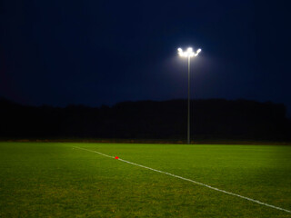 Fototapeta na wymiar Training ground with grass illuminated by modern powerful LED lights. Efficient modern technology. Nobody.