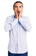 Young handsome man wearing business clothes afraid and shocked, surprise and amazed expression with hands on face