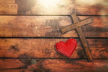 Red heart and wooden cross on desk