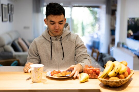 Hombre joven tomando el desayuno saludable en su casa por la ma&ntilde;ana.