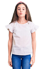 Fototapeta premium Cute hispanic child girl wearing casual white tshirt looking at the camera blowing a kiss on air being lovely and sexy. love expression.