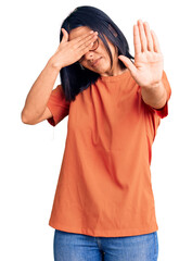 Young beautiful latin woman wearing casual clothes covering eyes with hands and doing stop gesture with sad and fear expression. embarrassed and negative concept.