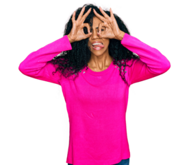 Middle age african american woman wearing casual clothes doing ok gesture like binoculars sticking tongue out, eyes looking through fingers. crazy expression.