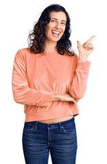 Young beautiful hispanic woman wearing casual clothes with a big smile on face, pointing with hand and finger to the side looking at the camera.