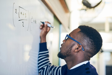 Just try until you get it right. Cropped shot of a young man writing on a whiteboard in a classroom.