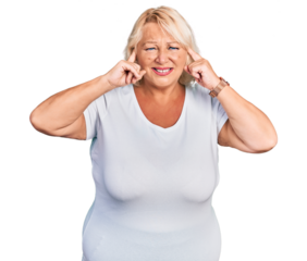Middle age blonde woman wearing casual white t shirt covering ears with fingers with annoyed expression for the noise of loud music. deaf concept.