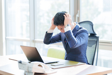 オフィスで頭を抱えるビジネスマン