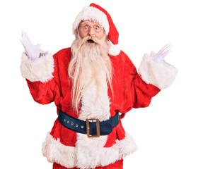 Old senior man with grey hair and long beard wearing traditional santa claus costume celebrating crazy and amazed for success with arms raised and open eyes screaming excited. winner concept