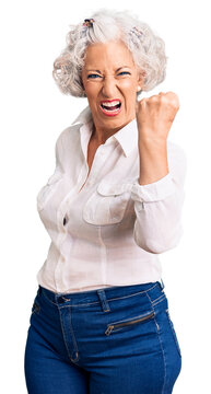 Senior grey-haired woman wearing casual clothes angry and mad raising fist frustrated and furious while shouting with anger. rage and aggressive concept.
