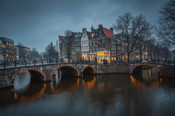 Fototapeta premium Evening panoramic view of the famous historic center with lights, bridges, canals and traditional Dutch houses in Amsterdam, Netherlands