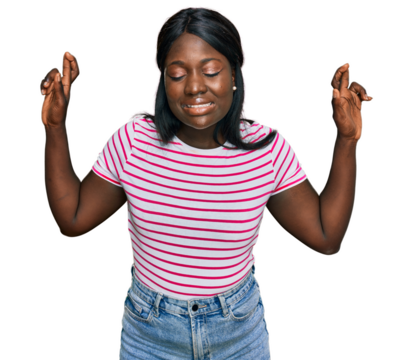 African young woman wearing casual striped t shirt gesturing finger crossed smiling with hope and eyes closed. luck and superstitious concept.